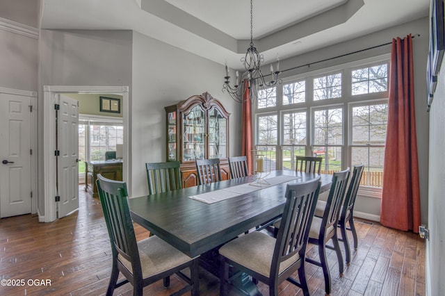 dining space featuring an inviting chandelier, wood-type flooring, and a towering ceiling
