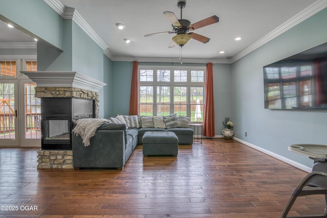 living room featuring a stone fireplace, hardwood / wood-style flooring, a ceiling fan, and crown molding
