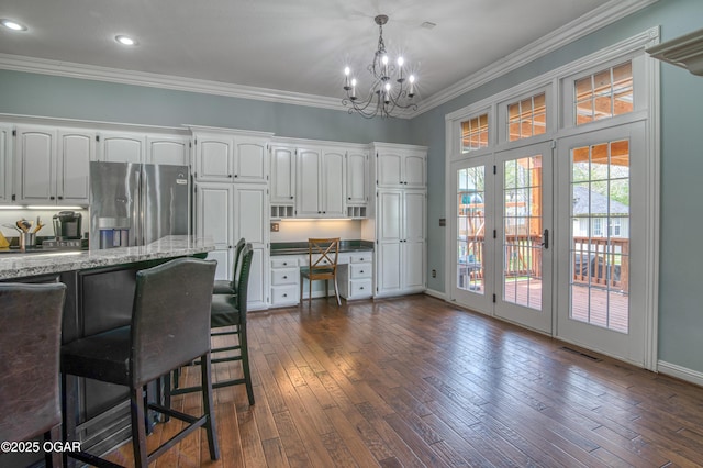 interior space with dark wood finished floors, an inviting chandelier, visible vents, french doors, and crown molding