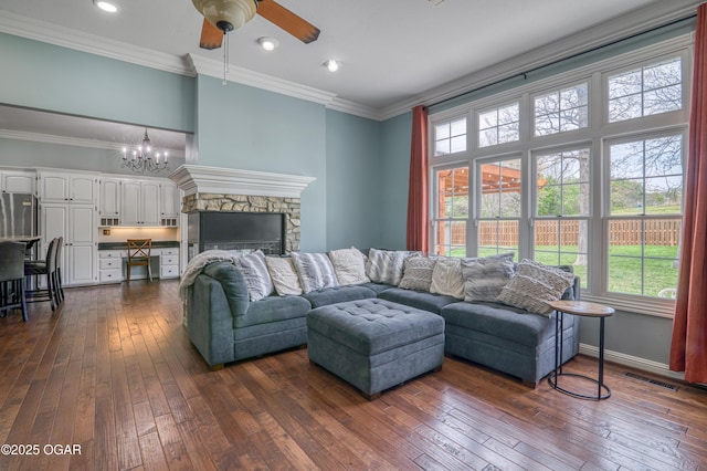 living room featuring dark wood finished floors, a wealth of natural light, ceiling fan with notable chandelier, and crown molding