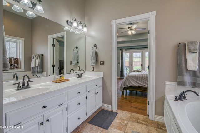 bathroom featuring double vanity, a sink, ceiling fan, and ensuite bathroom