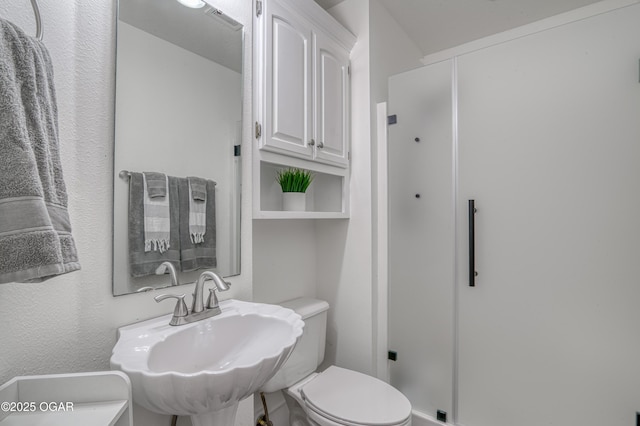 bathroom featuring toilet, a sink, and a shower stall