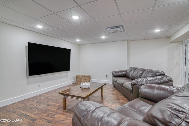 living area with wood finished floors, visible vents, a paneled ceiling, and baseboards