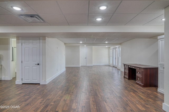 finished below grade area featuring a paneled ceiling, visible vents, baseboards, and dark wood-type flooring