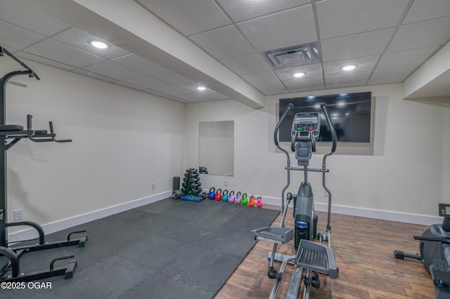 exercise area with visible vents, a drop ceiling, wood finished floors, and baseboards