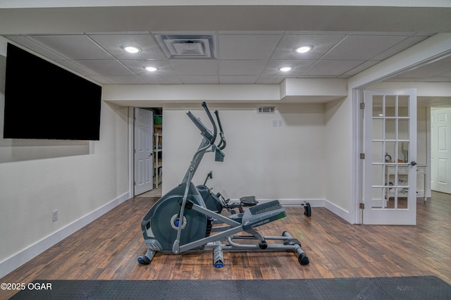 workout area with baseboards, wood finished floors, and a paneled ceiling