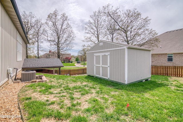 view of yard with central AC, a fenced backyard, a shed, and an outbuilding