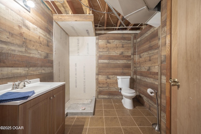 bathroom featuring tile patterned floors, wood walls, vanity, and toilet
