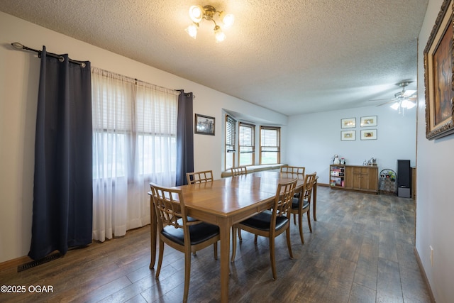 dining area featuring a ceiling fan, visible vents, a textured ceiling, and dark wood finished floors