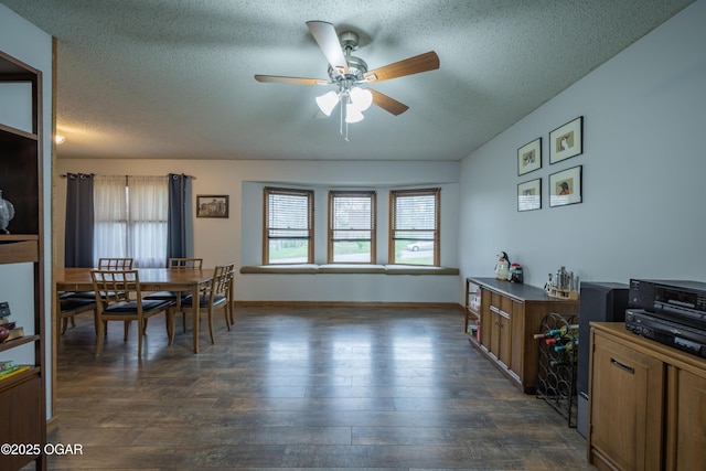 dining room with dark wood-style flooring, a textured ceiling, baseboards, and ceiling fan