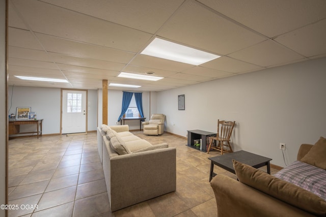 living area featuring baseboards, a paneled ceiling, and light tile patterned floors