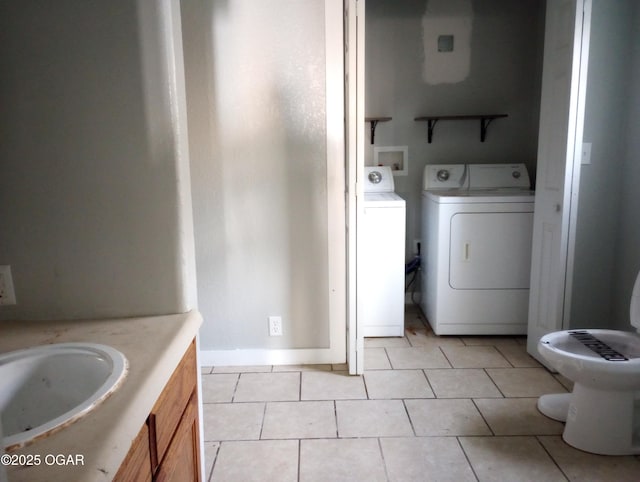 laundry area with washing machine and clothes dryer, a sink, laundry area, and light tile patterned floors
