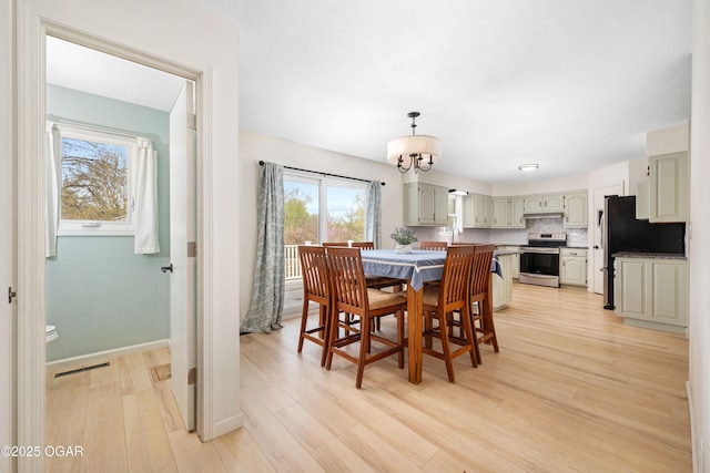 dining room with baseboards, an inviting chandelier, light wood-style flooring, and visible vents