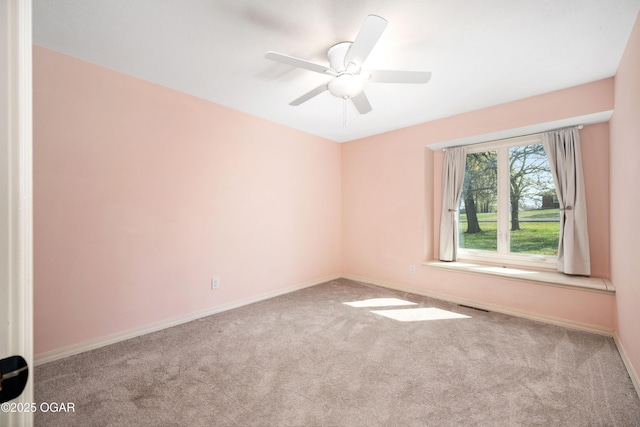 carpeted spare room with baseboards, a ceiling fan, and visible vents