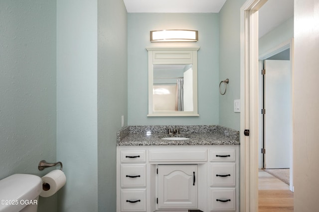 bathroom featuring vanity, toilet, and wood finished floors