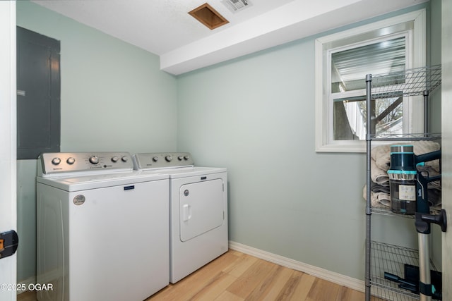 laundry area with electric panel, laundry area, separate washer and dryer, baseboards, and light wood-style floors