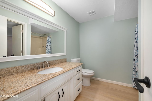 bathroom featuring toilet, wood finished floors, visible vents, baseboards, and vanity