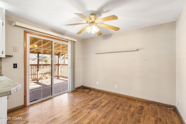 unfurnished room featuring light wood-style floors, a textured ceiling, baseboards, and ceiling fan