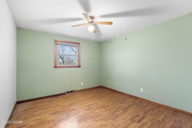 spare room with ceiling fan, baseboards, visible vents, and light wood-style flooring