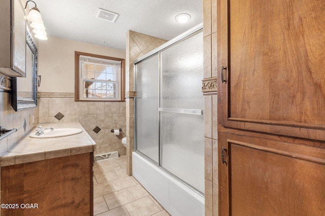 full bath featuring tile patterned floors, visible vents, toilet, vanity, and tile walls