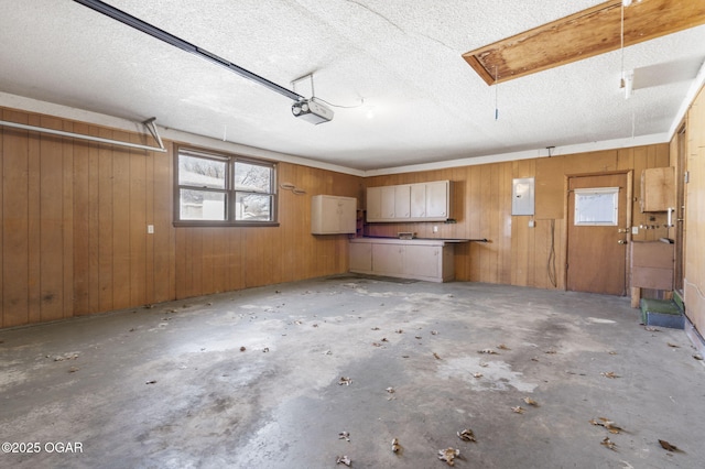 garage with electric panel, wood walls, and a garage door opener