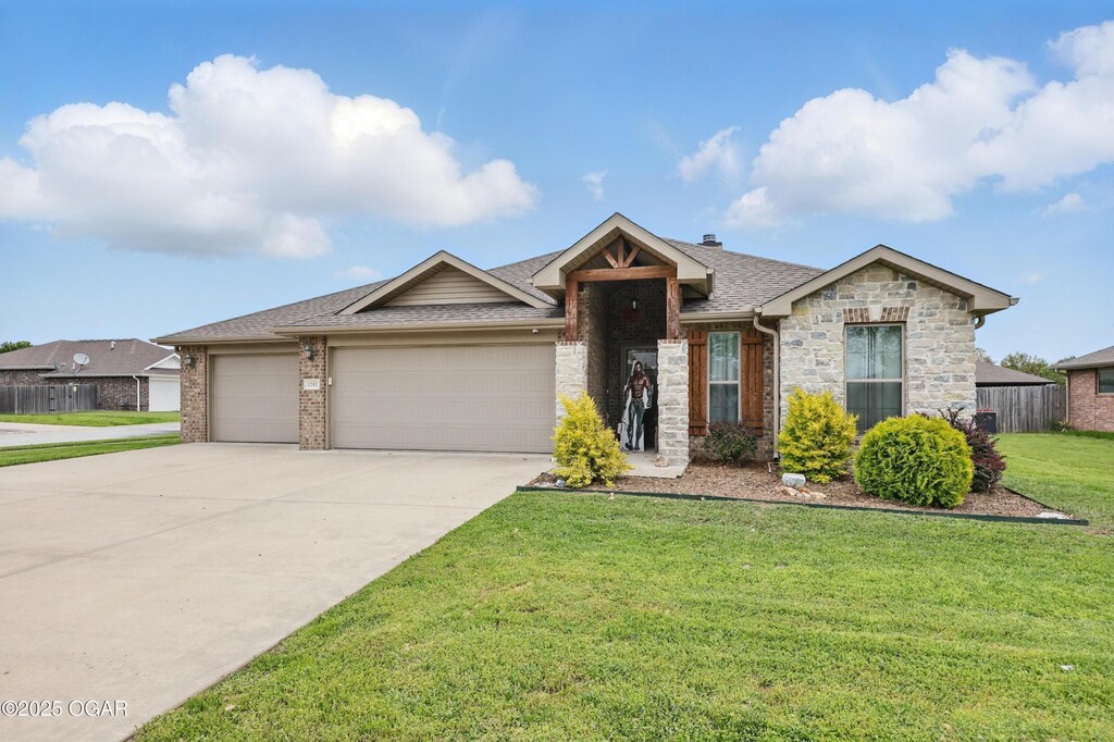 1201 W Par Cir, Neosho, MO 64850 - ranch-style home with driveway, an attached garage, a front lawn, a shingled roof, and stone siding