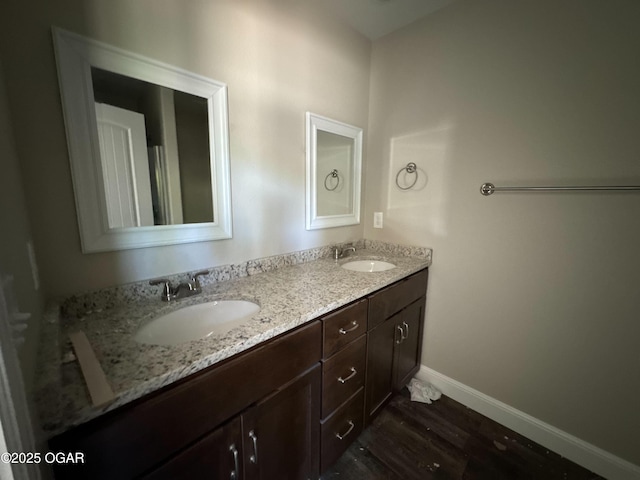 full bathroom with double vanity, wood finished floors, baseboards, and a sink