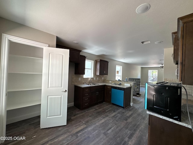 kitchen featuring a peninsula, dark wood finished floors, dishwasher, and a sink