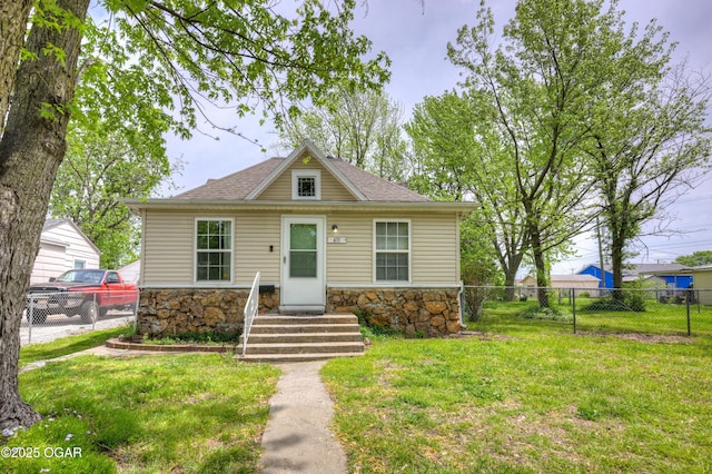 bungalow-style home featuring fence, a front lawn, and stone siding
