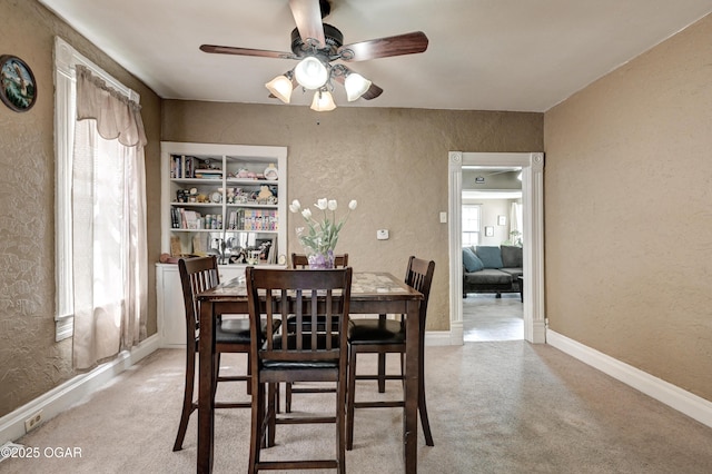 dining area featuring a ceiling fan, a textured wall, and baseboards