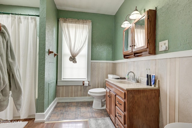 full bath with curtained shower, vanity, a wainscoted wall, toilet, and wooden walls