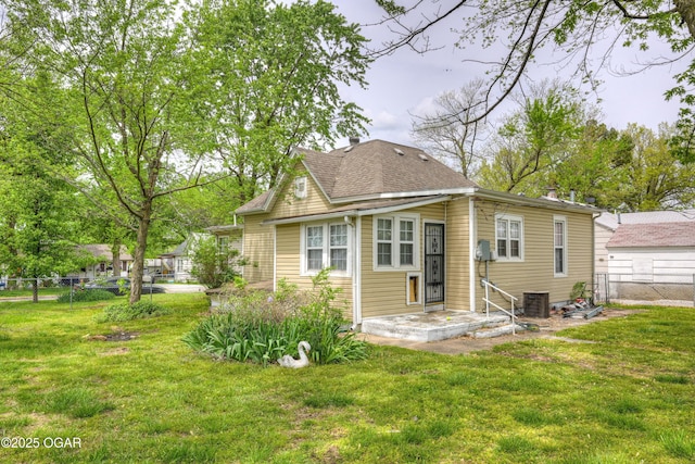 rear view of house with a yard, central AC unit, and a fenced backyard