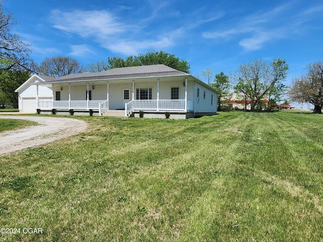 305 E Maple St, Liberal, MO 64762 - farmhouse featuring covered porch, dirt driveway, a front yard, and an attached garage