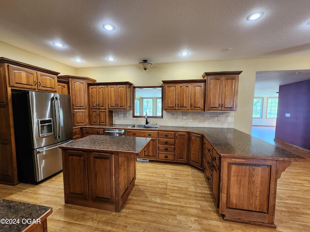 305 E Maple St, Liberal, MO 64762 - kitchen featuring stainless steel appliances, a textured ceiling, a sink, light wood-type flooring, and a peninsula