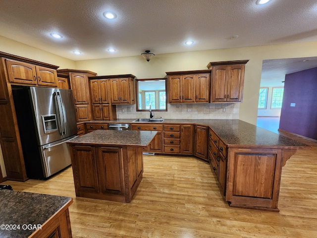 305 E Maple St, Liberal, MO 64762 - kitchen featuring a textured ceiling, a sink, appliances with stainless steel finishes, light wood finished floors, and a peninsula