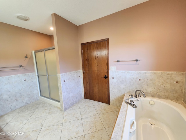 305 E Maple St, Liberal, MO 64762 - bathroom with tile walls, a shower stall, a wainscoted wall, a garden tub, and tile patterned flooring