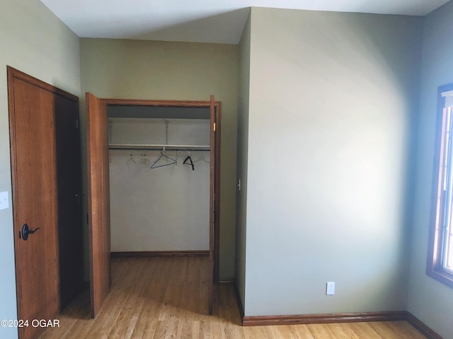 305 E Maple St, Liberal, MO 64762 - unfurnished bedroom featuring wood finished floors, baseboards, and a closet
