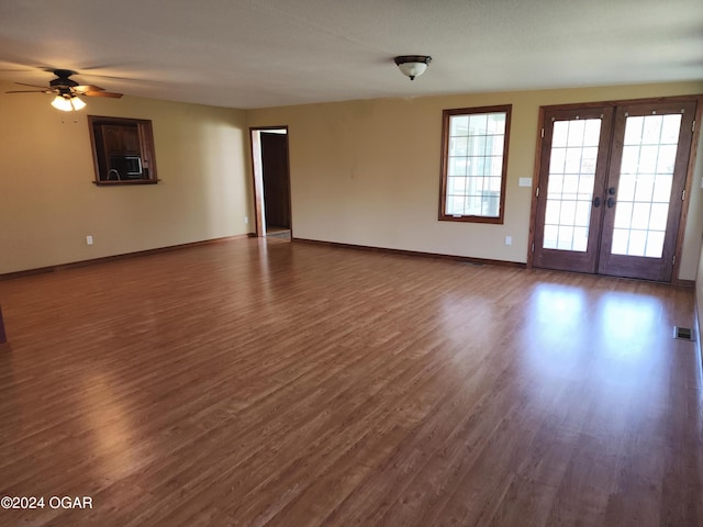305 E Maple St, Liberal, MO 64762 - unfurnished living room with french doors, dark wood finished floors, and baseboards