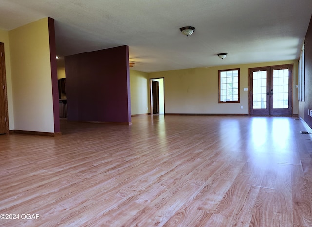 305 E Maple St, Liberal, MO 64762 - unfurnished living room with ceiling fan, light wood-style flooring, french doors, and baseboards