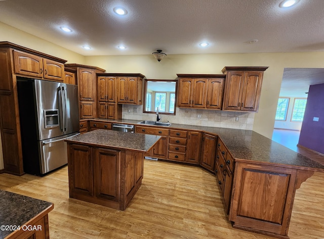 305 E Maple St, Liberal, MO 64762 - kitchen with a sink, dark countertops, stainless steel appliances, light wood-type flooring, and a peninsula