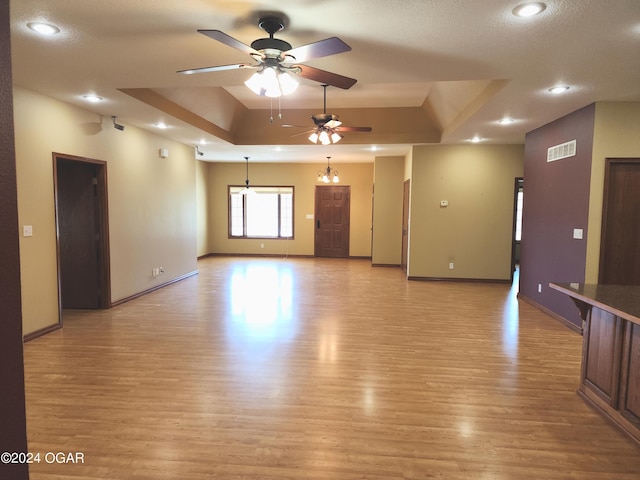 305 E Maple St, Liberal, MO 64762 - unfurnished living room with a ceiling fan, visible vents, light wood-style flooring, and a raised ceiling