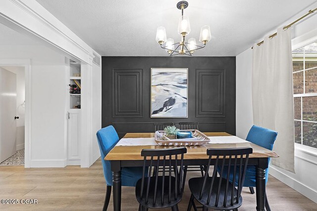 dining room with a chandelier, healthy amount of natural light, light wood-type flooring, and baseboards