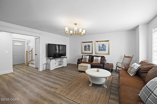 living area with a chandelier, wood finished floors, baseboards, and stairs