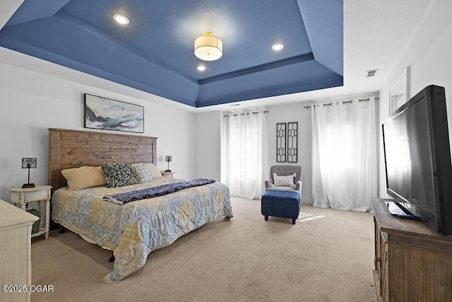 carpeted bedroom with a raised ceiling and recessed lighting