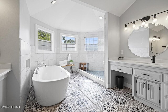 bathroom with lofted ceiling, a freestanding tub, tile walls, vanity, and a tile shower