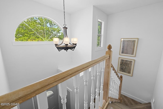 staircase with a chandelier, baseboards, and wood finished floors