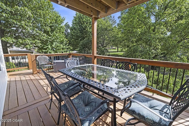 wooden terrace featuring outdoor dining space and view of scattered trees