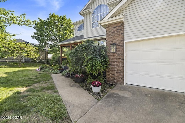 view of side of home featuring a garage, brick siding, a yard, and concrete driveway