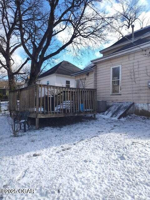 snow covered rear of property with a deck