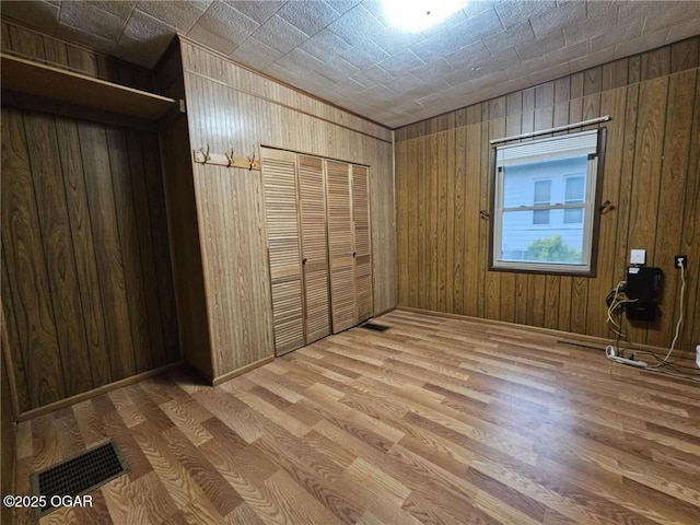 105 S Elm St, Mulberry, KS 66756 - unfurnished bedroom featuring wooden walls, wood finished floors, and visible vents